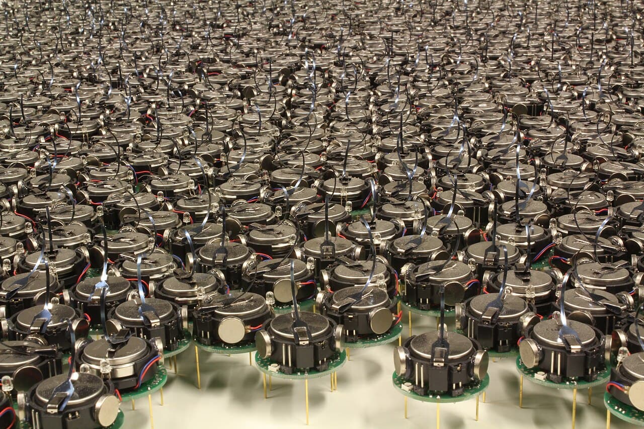 A large group of small round Kilobot research robots gathered together.